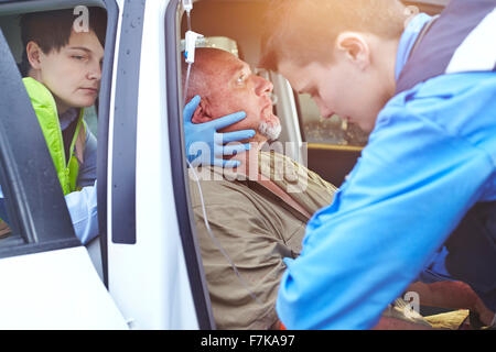 Gli operatori di soccorso attentamente tendente ad auto vittima di incidenti in auto Foto Stock