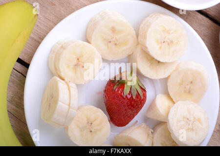 Un sano di fragole e banane sezioni sullo sfondo di legno Foto Stock