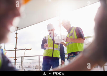 Lavoratori edili con tavoletta digitale al sito in costruzione Foto Stock