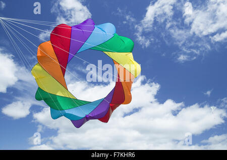 Un arcobaleno colorato aquilone vola in un cielo blu con il bianco puffy nuvole sul 15 aprile 2007, presso la chiesa di Santa Barbara il Kite Festival di Santa Barbara City College, affacciato sull'Oceano Pacifico. Foto Stock