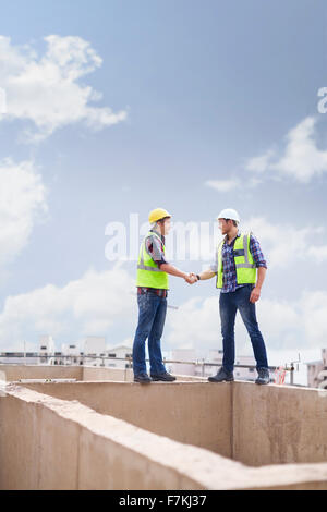 Lavoratori edili di handshaking highrise sito in costruzione Foto Stock
