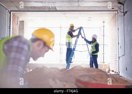 Operaio edile sulla scaletta a sito in costruzione Foto Stock