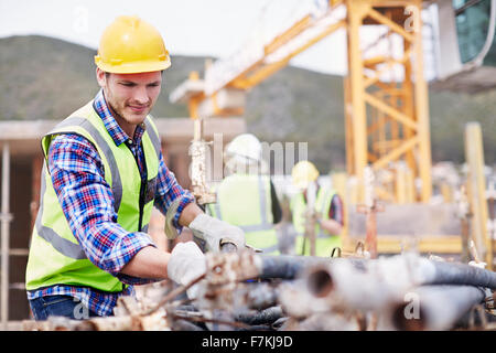 Operaio edile lavora al sito in costruzione Foto Stock