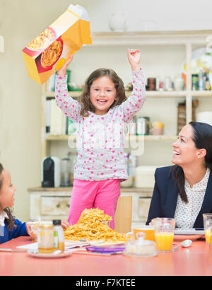 Ritratto ragazza entusiastica acclamare con scatola di cereali al tavolo per la colazione Foto Stock