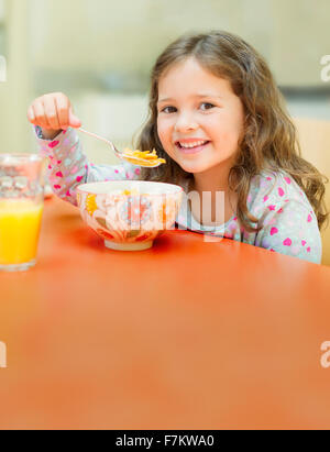 Ritratto sorridente ragazza mangiare cereali al tavolo per la colazione Foto Stock