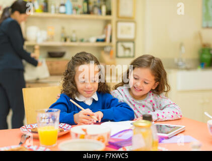 Le ragazze di fare i compiti al tavolo per la colazione Foto Stock