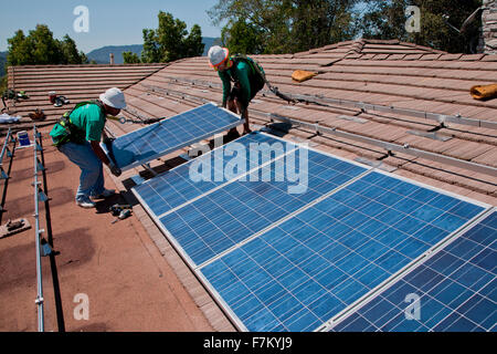 Due maschi lavoratori solare installare pannelli solari su home in vista di quercia, la California del Sud Foto Stock