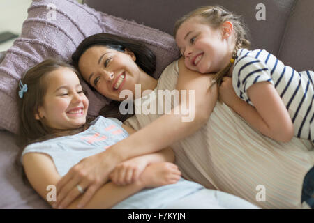 Affettuosa madre e figlie coccole sul divano Foto Stock