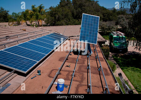 Due maschi lavoratori solare installare pannelli solari su home in vista di quercia, la California del Sud Foto Stock