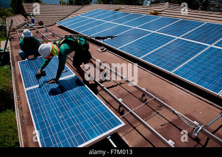 Due maschi lavoratori solare installare pannelli solari su home in vista di quercia, la California del Sud Foto Stock