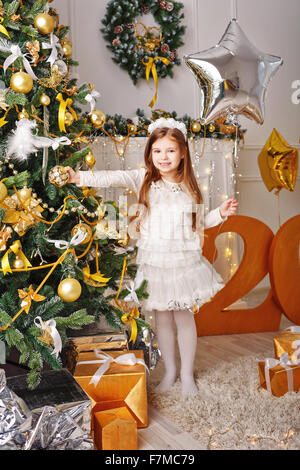 Bambina decora l'albero di Natale. Ragazza con un palloncino. Vacanza e divertimento. Foto Stock