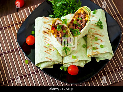 Burrito si avvolge con carne macinata e verdure su un sfondo di legno Foto Stock