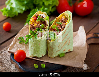 Burrito si avvolge con carne macinata e verdure su un sfondo di legno Foto Stock