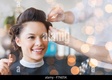 Donna felice con la stilista rendendo pettinatura a salon Foto Stock