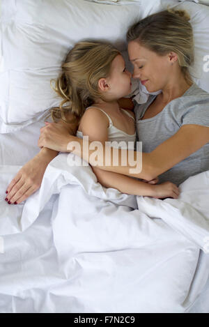 Madre e figlia nel letto abbracciando Foto Stock