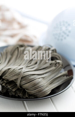 Tagliatelle nere con calamari seppia inchiostro sulla piastra nera Foto Stock