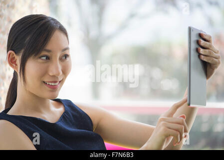 Giovane donna utilizzando una tavoletta digitale per prendere un selfie Foto Stock