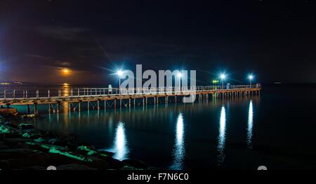 Il molo di Limassol in Area Enaerios a Cipro. Una vista notturna della città luci allineando la luna che sorge dal mare refl Foto Stock