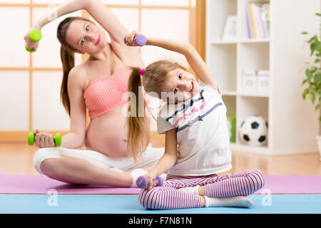 La donna incinta e il suo bambino più anziano facendo esercizi di fitness con manubri Foto Stock