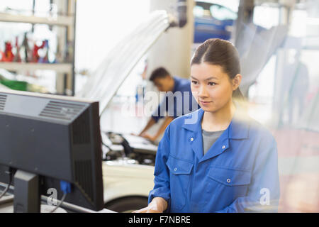 Meccanico femmina lavorando al computer in negozio di riparazioni auto Foto Stock