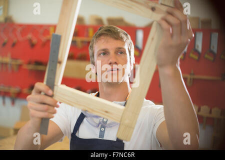Carpenter esaminando il legno in officina Foto Stock