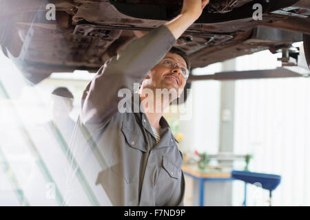 Lavoro meccanico sotto auto nel negozio di riparazioni auto Foto Stock