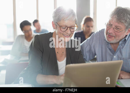 Gli studenti che studiano al computer portatile di educazione degli adulti classroom Foto Stock