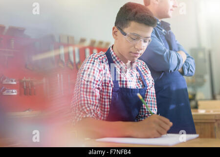 Studente di falegnameria di prendere appunti in officina Foto Stock