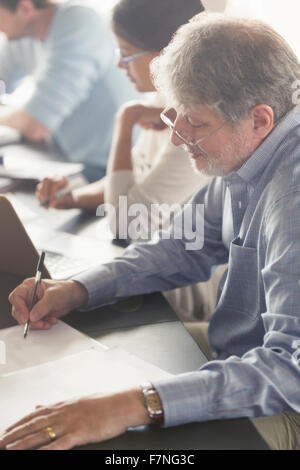 L'uomo facendo i compiti di scuola di educazione degli adulti classroom Foto Stock