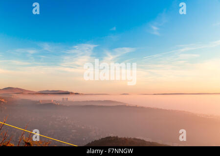 Sun va giù sulla città di Trieste mentre la baia è coperta dalla nebbia Foto Stock