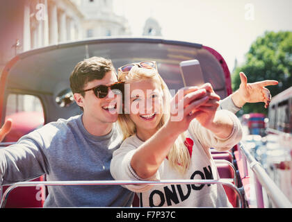 Giovane tenendo selfie su double-decker bus in Londra Foto Stock