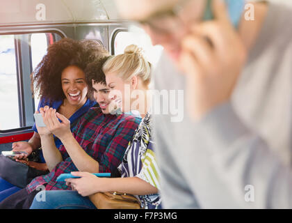 Gli amici gli sms con il telefono cellulare sul bus Foto Stock