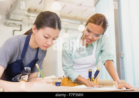 Falegnami femmina la stesura di piani in officina Foto Stock