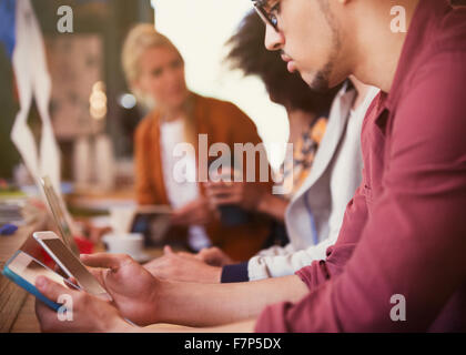 Uomo con tavoletta digitale e telefono cellulare in cafe Foto Stock