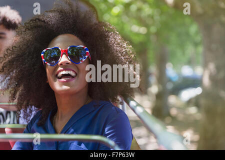 Donna entusiasta con Afro indossa il cuore gli occhiali di forma Foto Stock