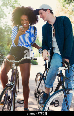 Gli amici sulle biciclette sms con il telefono cellulare Foto Stock