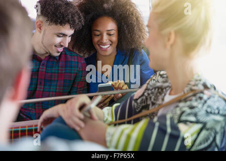 Gli amici gli sms con il telefono cellulare sul bus Foto Stock