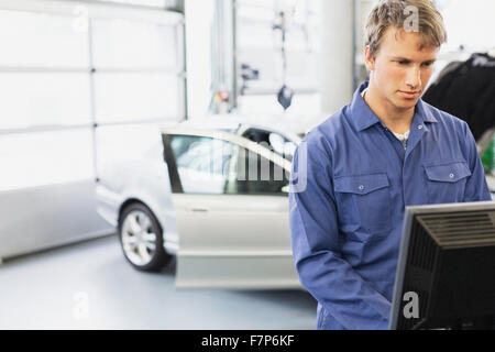 Lavoro meccanico al computer in negozio di riparazioni auto Foto Stock