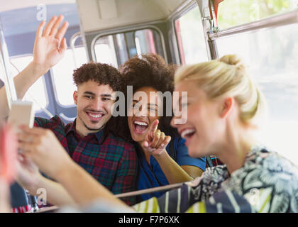 Amici entusiasti tenendo selfie sul bus Foto Stock