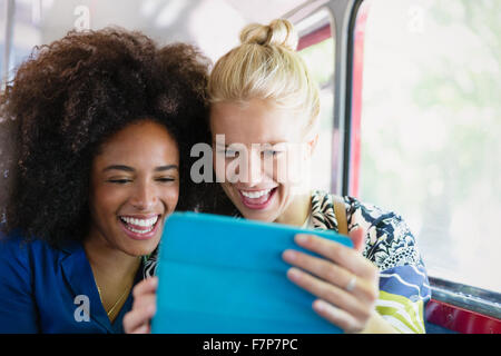 Amici entusiasti tenendo selfie con tavoletta digitale sul bus Foto Stock