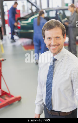 Ritratto sorridente imprenditore nel negozio di riparazioni auto Foto Stock