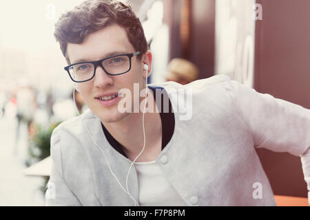 Ritratto uomo sorridente con occhiali ascoltando musica sulle cuffie Foto Stock