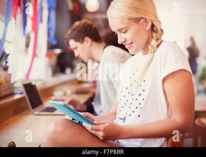 Donna bionda con tavoletta digitale in cafe Foto Stock