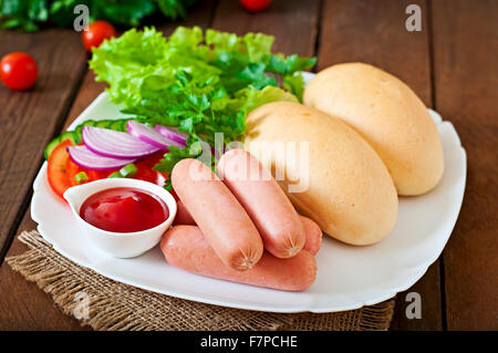Ingredienti per la preparazione di hot dog su una piastra bianca. Vista superiore Foto Stock