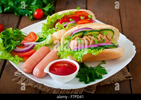 Hotdog con ketchup, senape, lattuga e verdure sul tavolo di legno Foto Stock