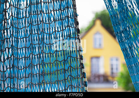 Casa di pesca / Blu rete da pesca e un vecchio bella casa gialla in background Foto Stock