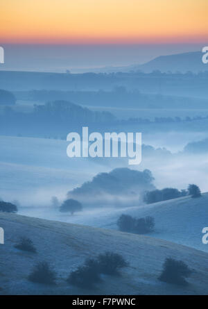 Una vista nebbiosa attraverso il Sussex Downs all'alba, da Ditchling Beacon, East Sussex. Foto Stock