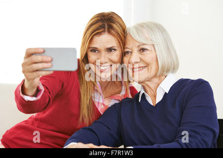 Giovani e vecchi donna prendendo selfie insieme con uno smartphone Foto Stock