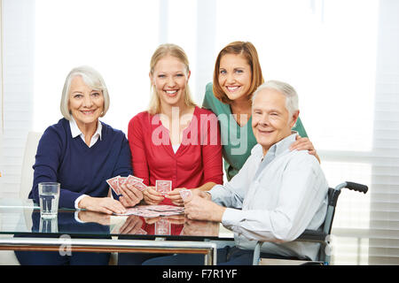 Personale Senior giocando a carte insieme con il nipote in casa di cura Foto Stock