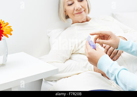 Senior donna nella casa di cura medicina arrivare da una pillola box Foto Stock